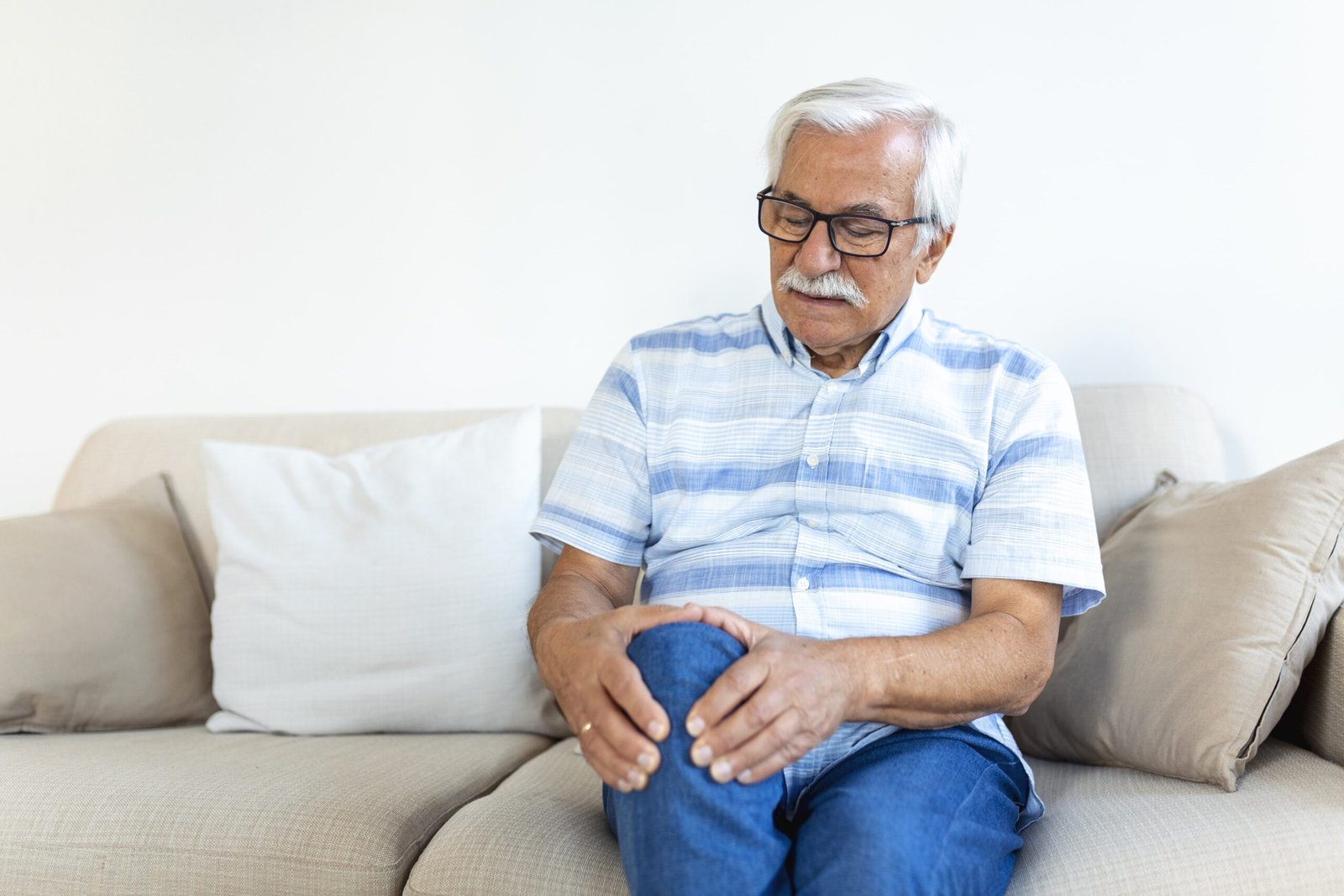 elderly-man-sitting-sofa-home-touching-his-painful-knee-people-health-care-problem-concept-unhappy-senior-man-suffering-from-knee-ache-home-min